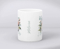 Preview: Weiße Keramiktasse mit Blumenmotiv, dem Zitat „We All Bloom Differently“ und personalisiertem Namen „Milena“, auf hellem Hintergrund präsentiert.